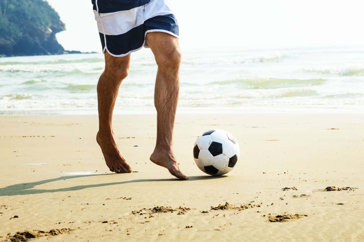 A man playing football on a beach