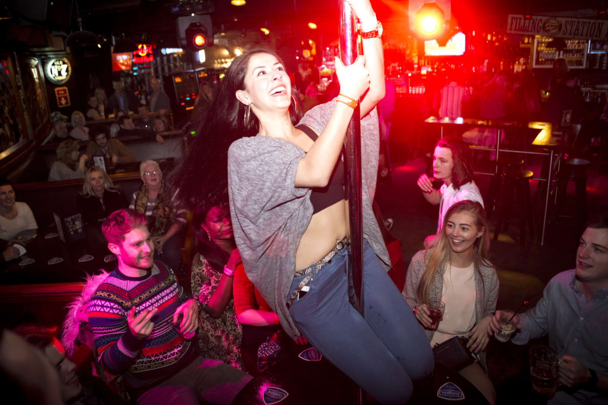 A woman dances on the bar during a bar crawl