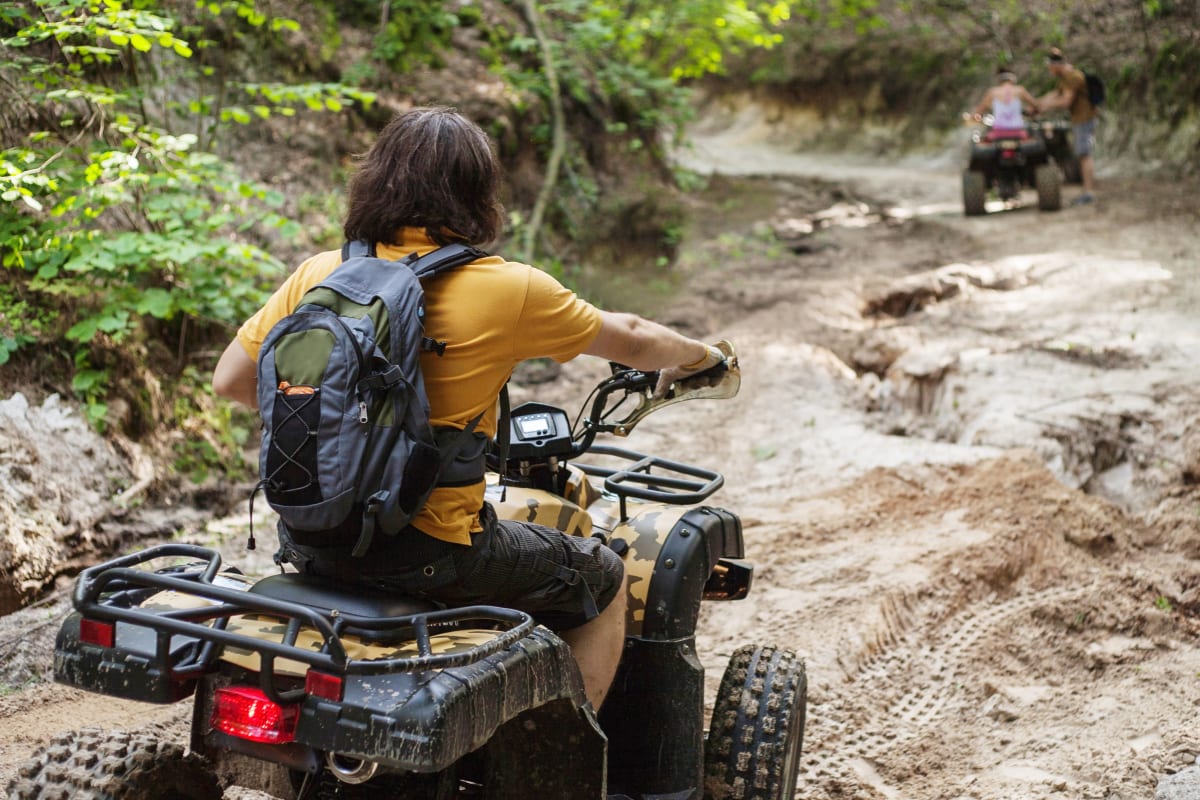 A quad biker riding on a muddy track