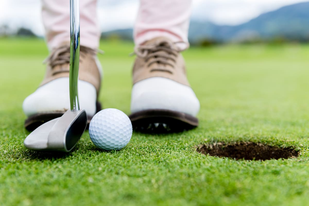 A golf putts a ball into a hole