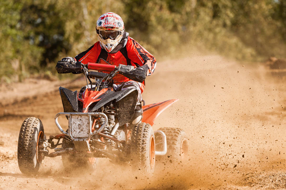 A quad biker riding on a muddy track