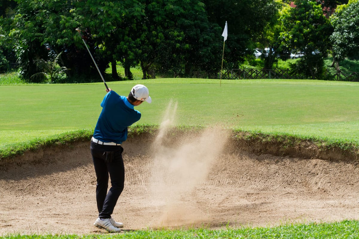 A golfer drives a ball up the fairway