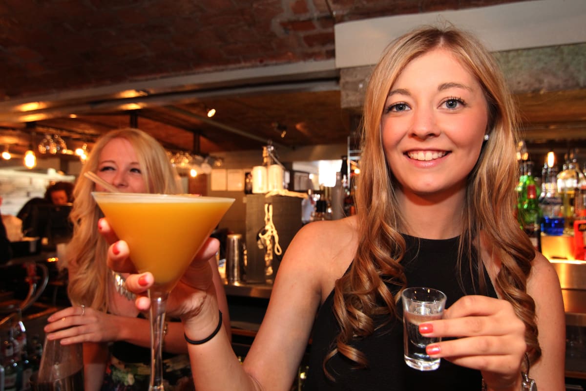 A smiling woman making cocktails