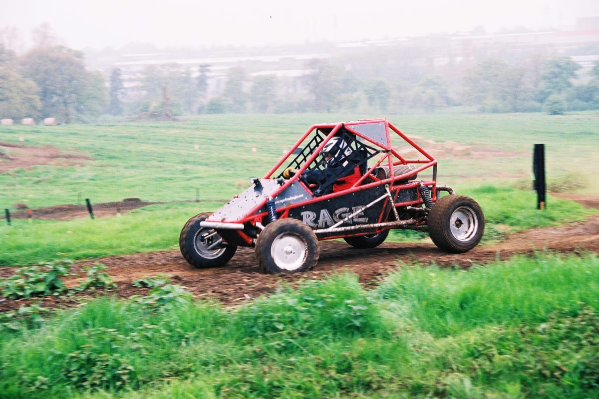 A man races a rage buggy around a muddy track