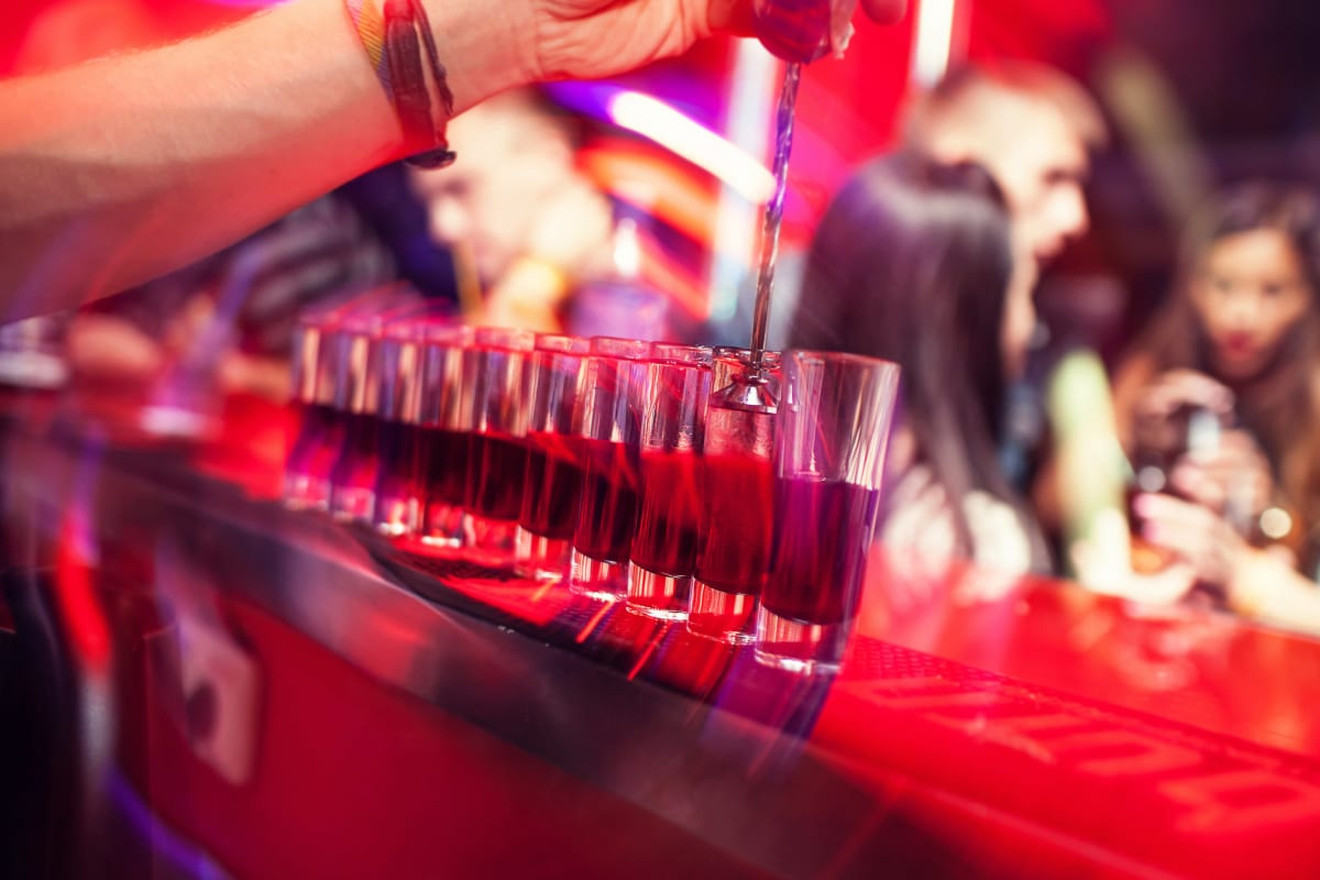 a bar man pours shots on a bar