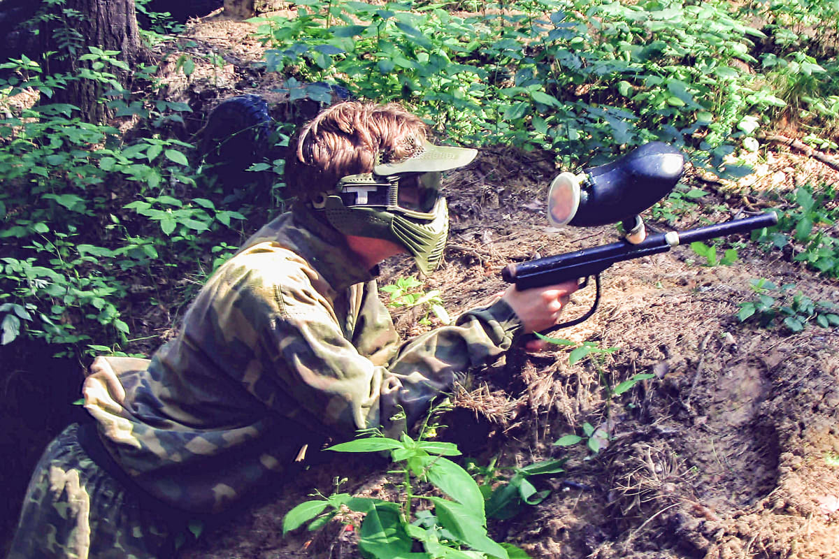 A man hiding in a hole during a paintball game re edit