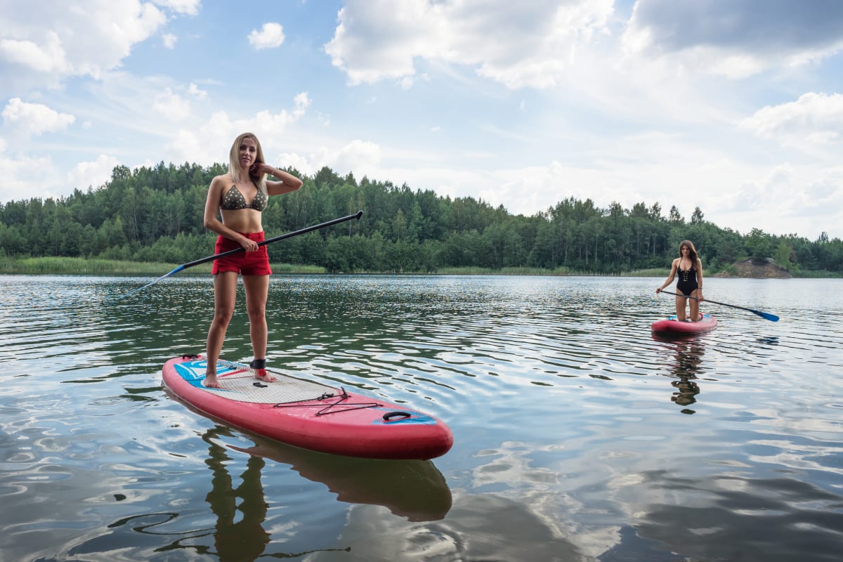 two women paddle boarding in lake in Latvia