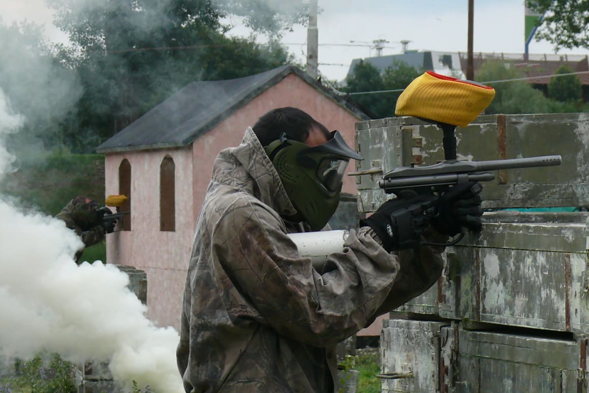 Two men playing paintball with smoke grenade