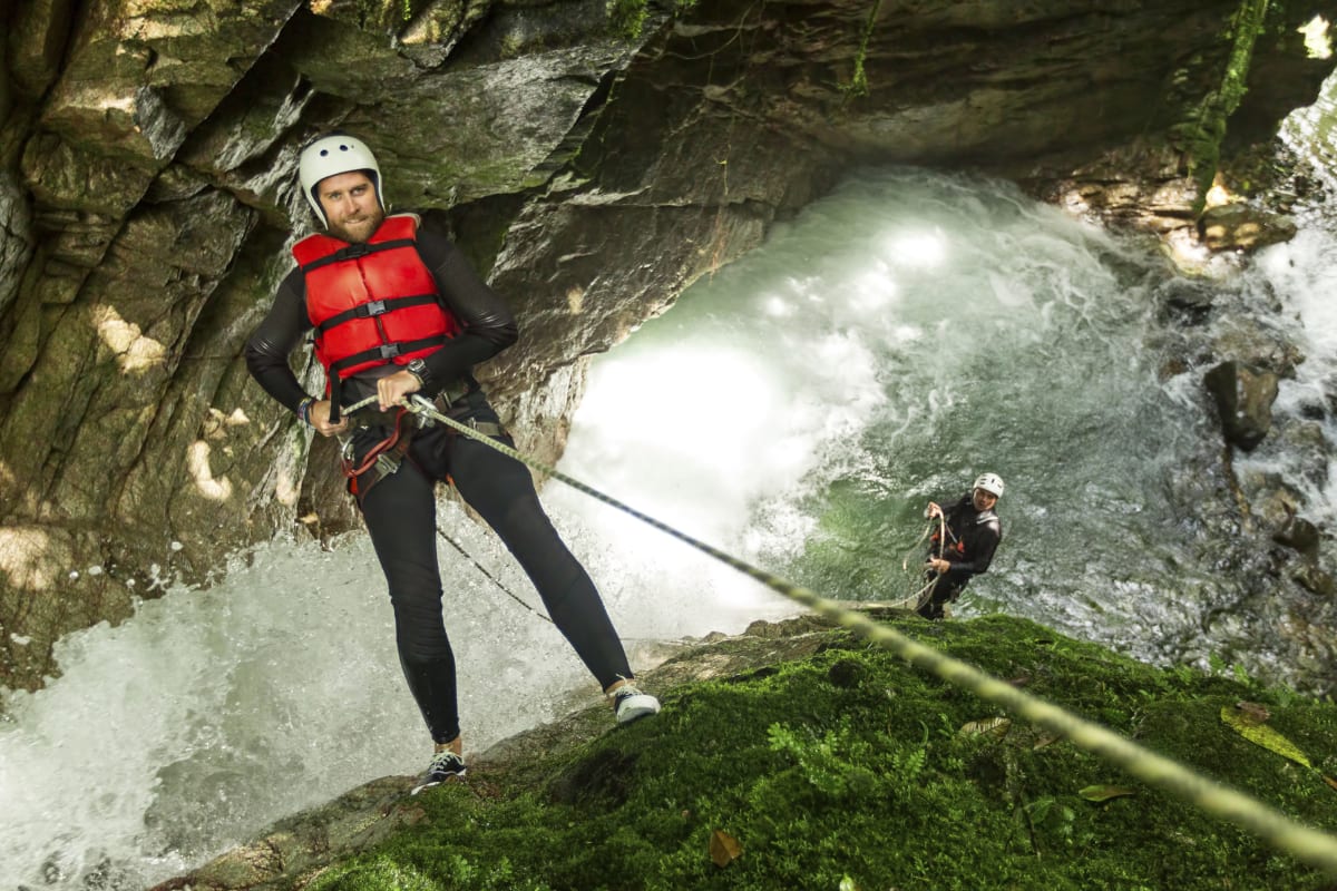 a man abseils from a cliff whilst canyoning