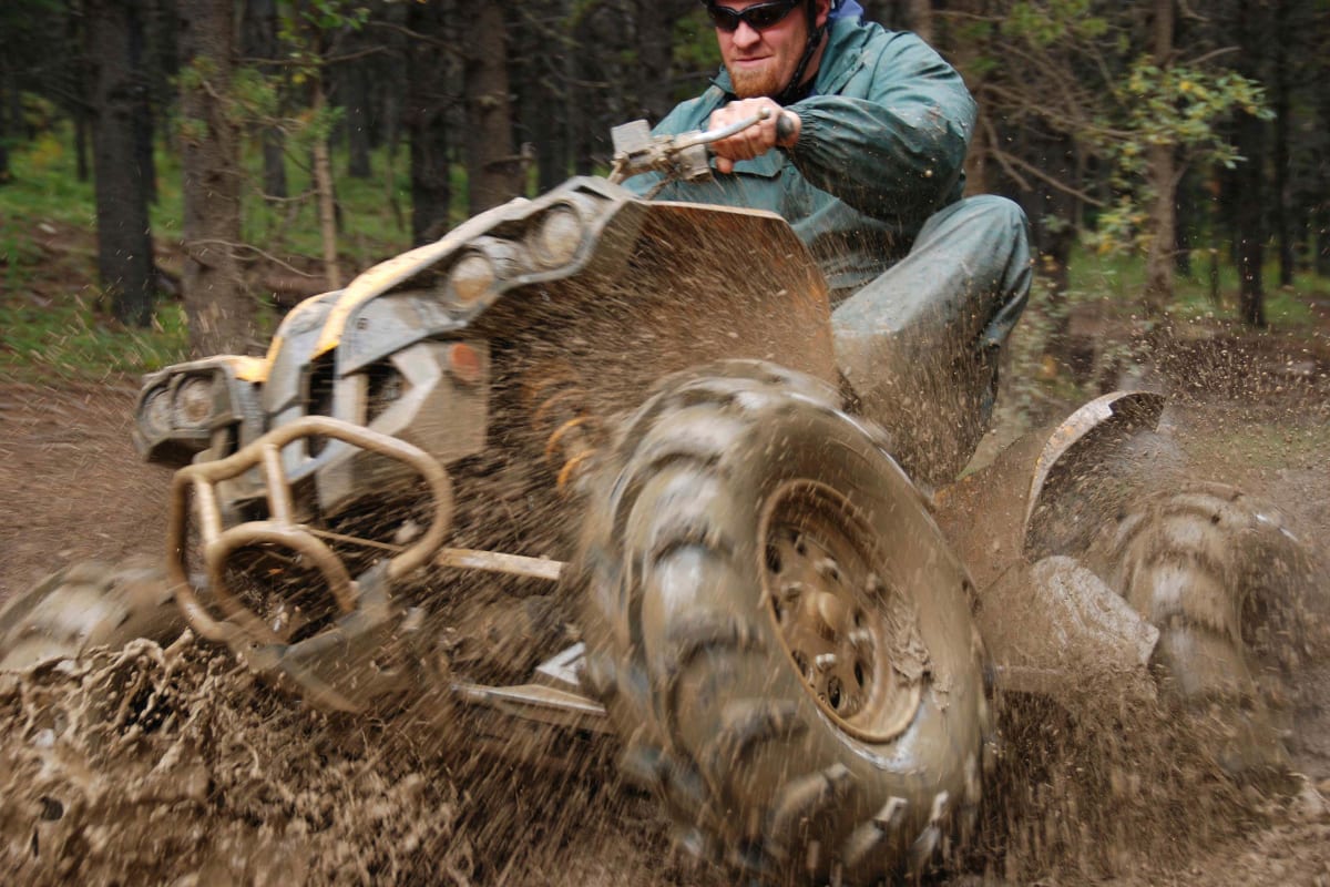 A man rides through the mud on a quad bike