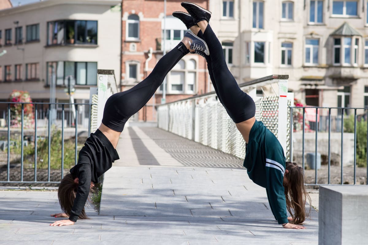 Girl practicing parkour doing a human pyramid on a bridge