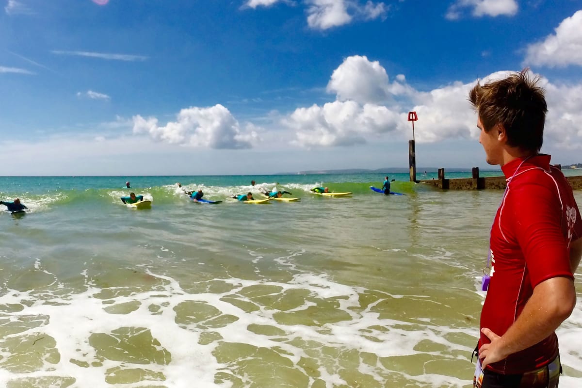 A happy stag group catching a wave on surfing lesson