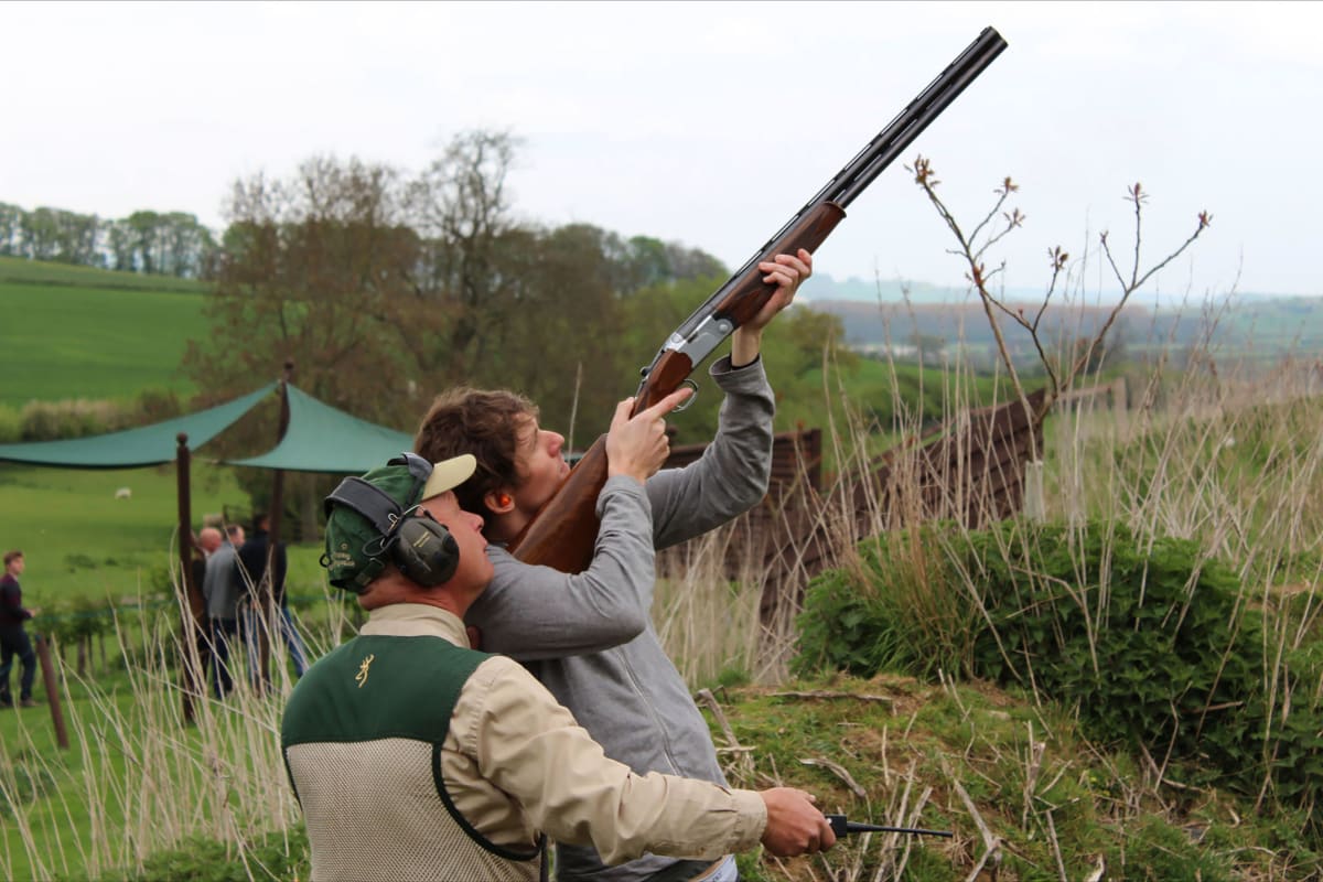 A man shoots a shotgun during clay pigeon shoot