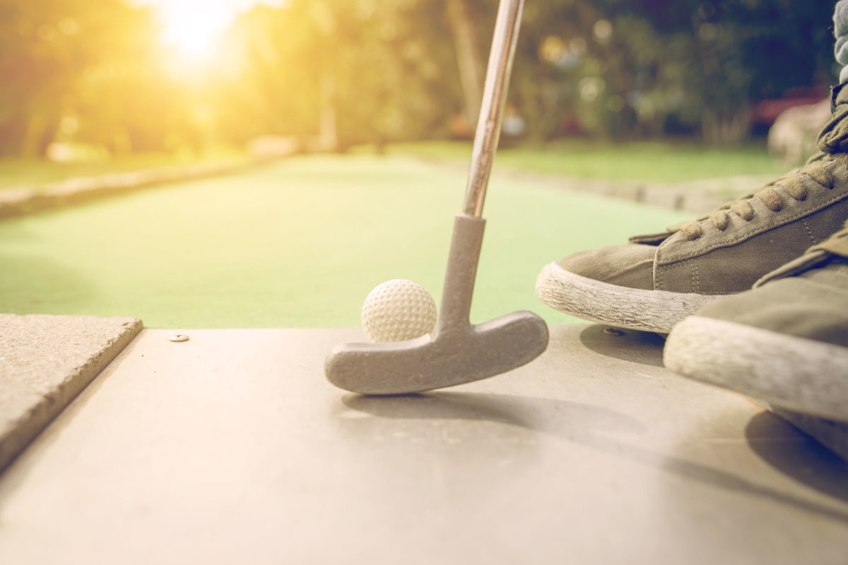 guy playing mini golf with sunset