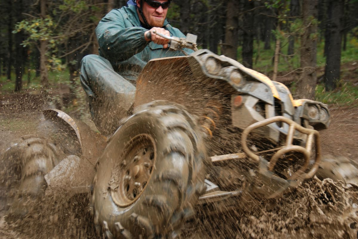 A man drives a quad through the mud