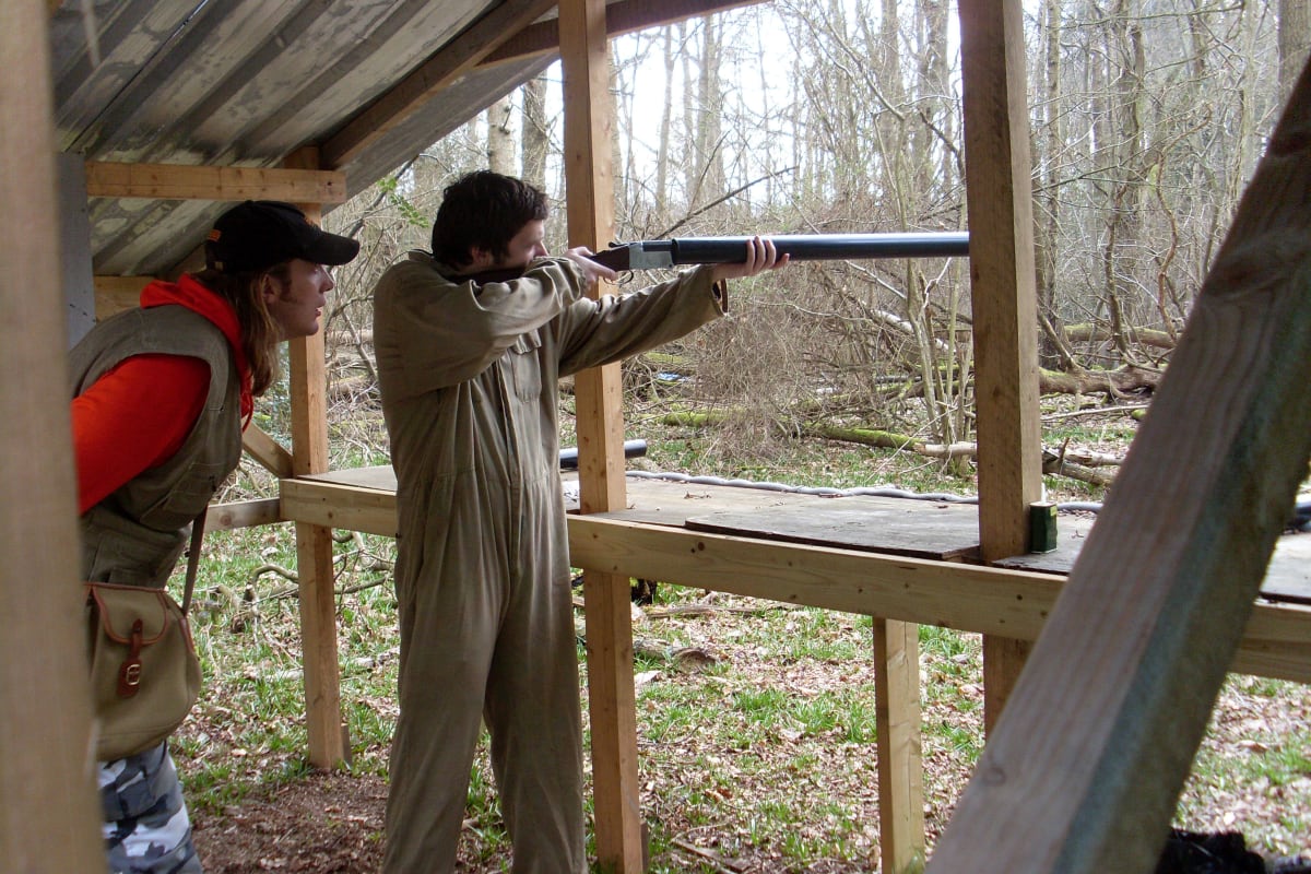A man aims a shotgun dring clay pigeon shooting