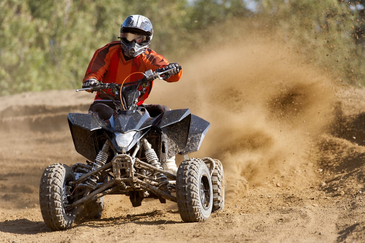 A quad biker riding on a muddy track