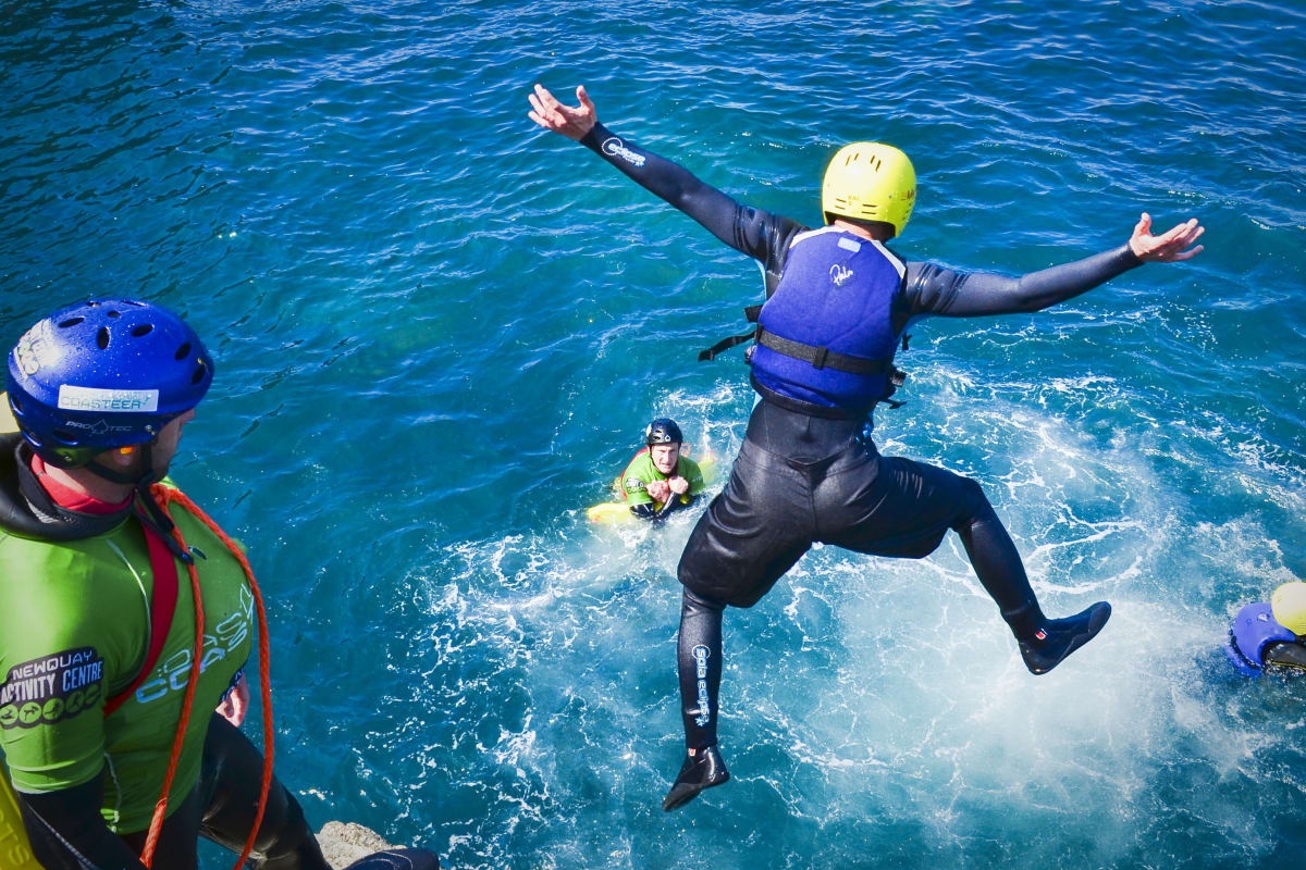 man jumping from cliff coasteering