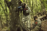 two guys playing paintball in the woods