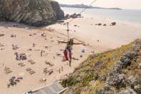 A woman on a zip line over Lusty Glaze beach Newquay