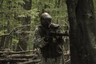 A man hides behind a sack during a game of paintball