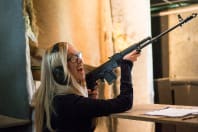 A woman shooting a machine gun AK47