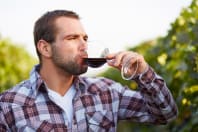 A man tasting wine in vineyard