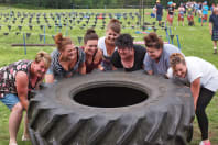 A smiling hen party lift a tire playing highland games