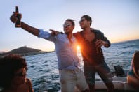 group of friends on boat with sunset and beers stags having fun