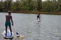 two men doing stand up paddle boarding on lake