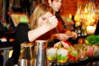 A woman making cocktails behind a bar