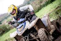 A muddy man on a quad bike