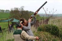 A man shoots a shotgun during clay pigeon shoot