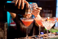 A man pours cocktails ata bar
