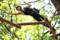 A woman climbs across a high ropes course