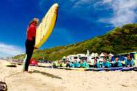 A laughing hen group lying on surfboards for a surfing lesson