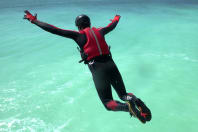 A man jumping from a cliff coasteering