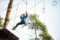 A man climbs across a high ropes course