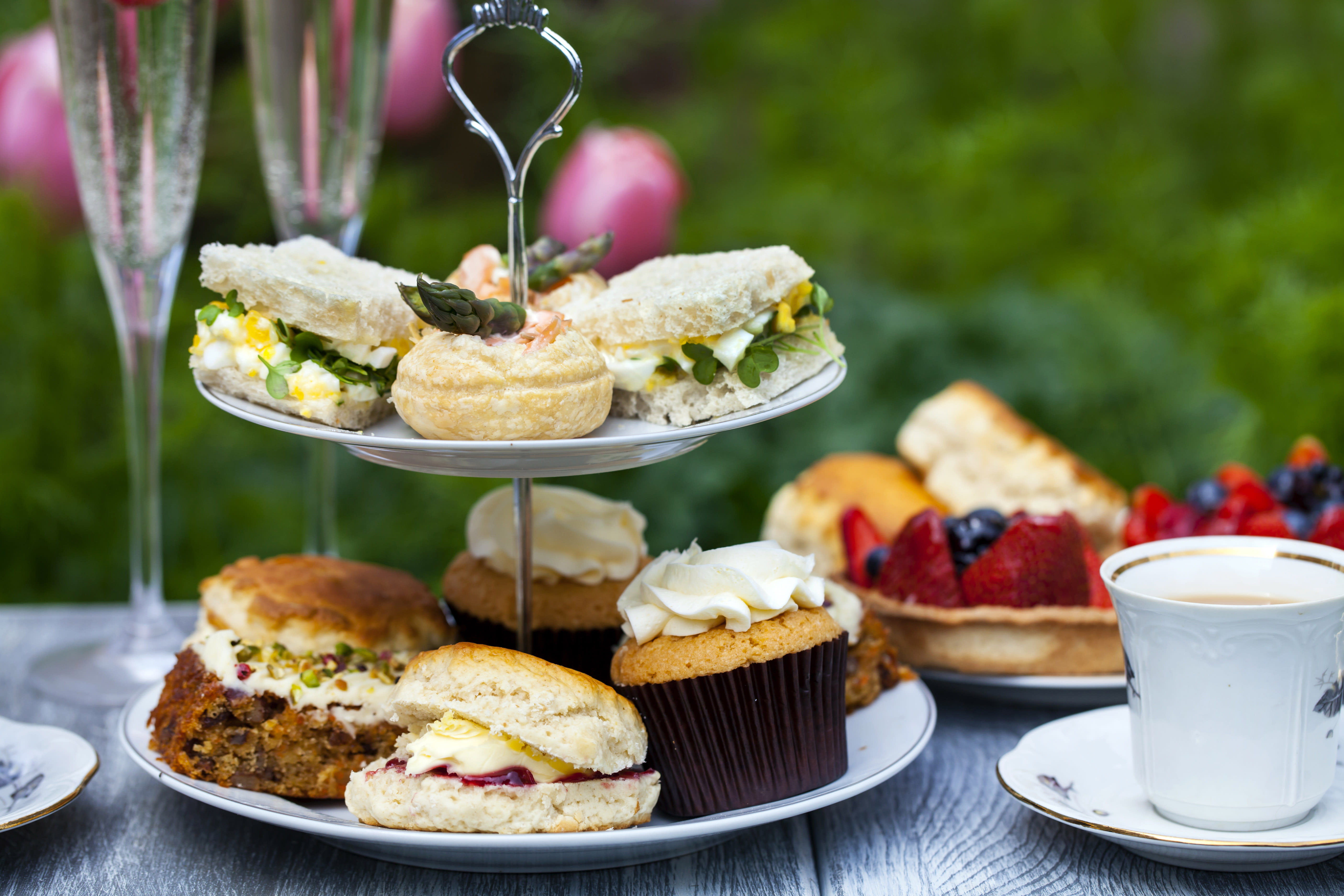 A cake tray with sandwiches and cakes on it