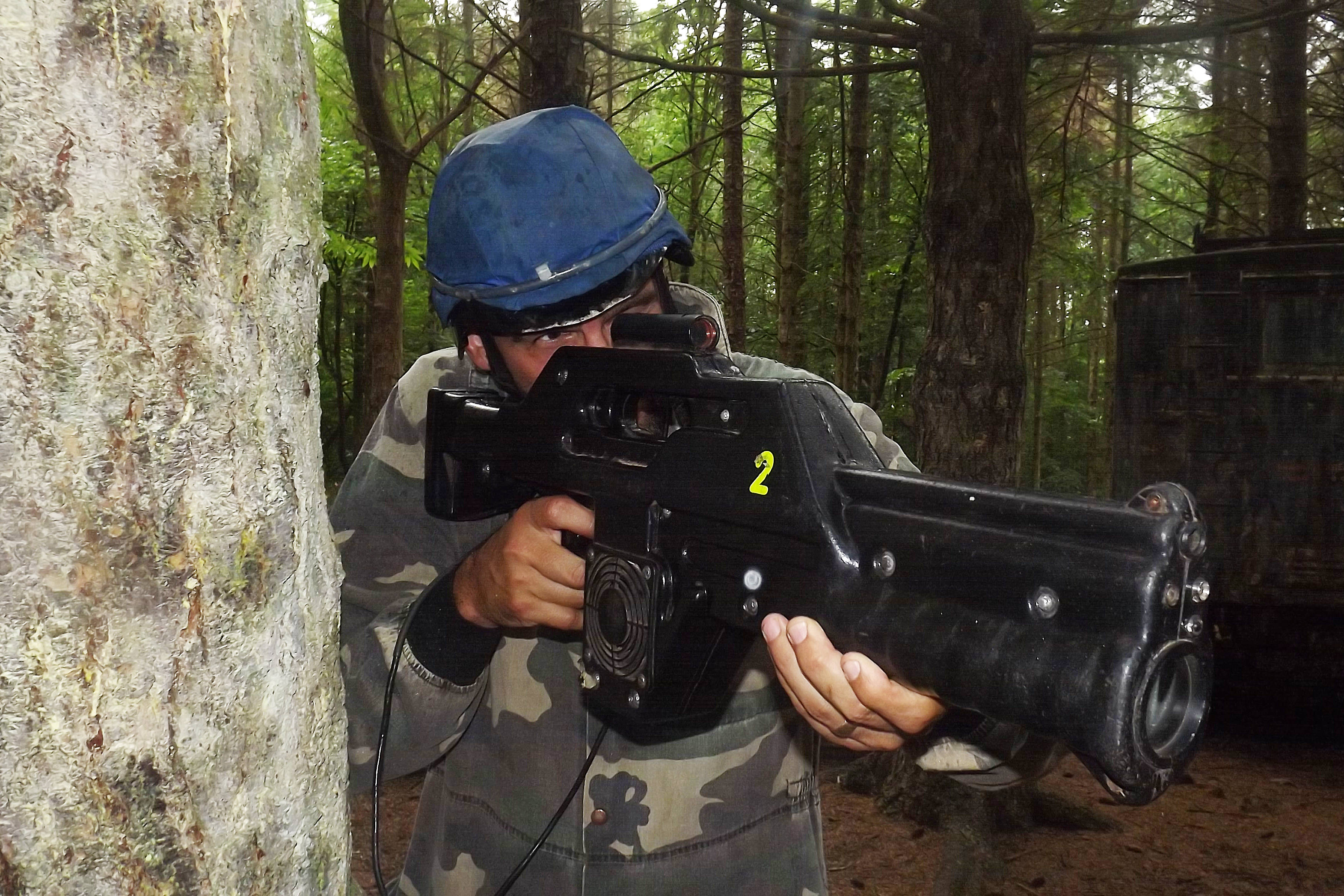 A man with hiding behind a tree playing pulse ranger game