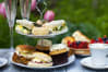 A cake tray with sandwiches and cakes on it