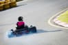 a woman races round a track whilst go karting