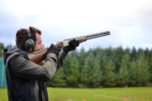 A man shoots a shotgun during clay pigeon shooting