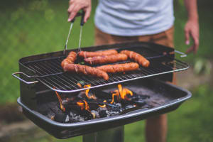 man putting sausages on barbeque