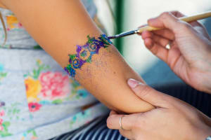 girl getting arm glitter decoration