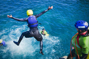 man jumping from cliff coasteering