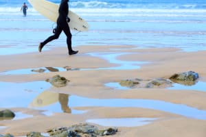 A man carries a surfboard on the beach
