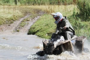 A man riding a quad bike through a river