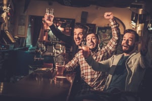 Men cheering whilst drinking beer in pub