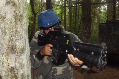 A man with hiding behind a tree playing pulse ranger game